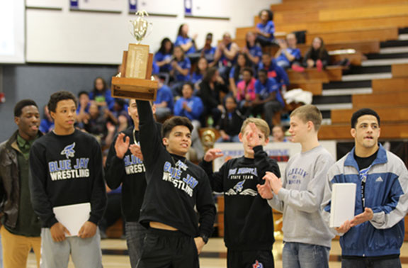 Gabe Padilla holds the league trophy as members of the state wrestling team are recognized.