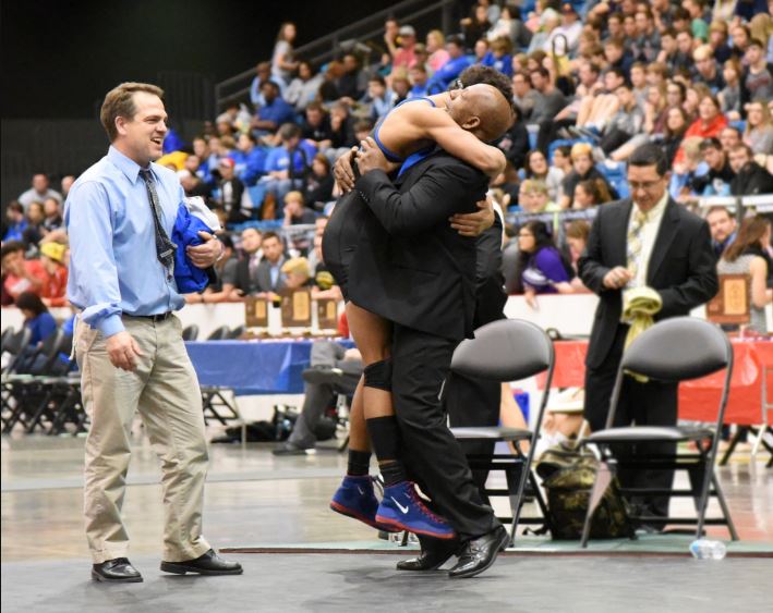Robert Laster, head wrestling coach embraces Aryus Jones after winning the 2016 Kansas State Championship.