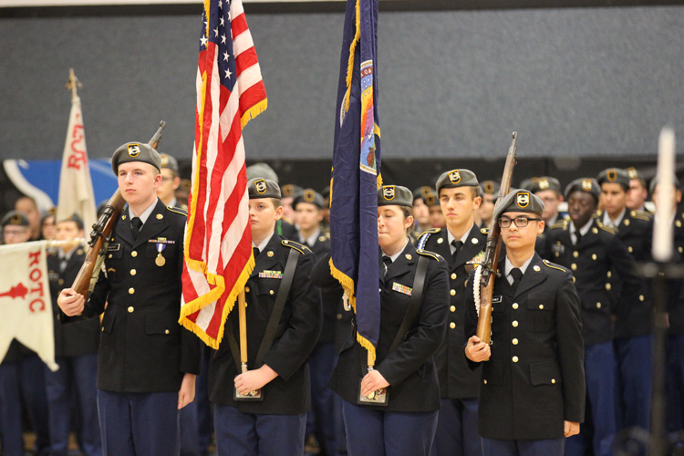 JROTC cadets present both the Kansas state  flag and American flag before marching  to center court.