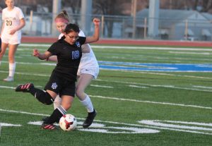 Senior Yurri Schott moves the ball down the field against Manhattan High School during the first varsity home game of the season on March 21. 